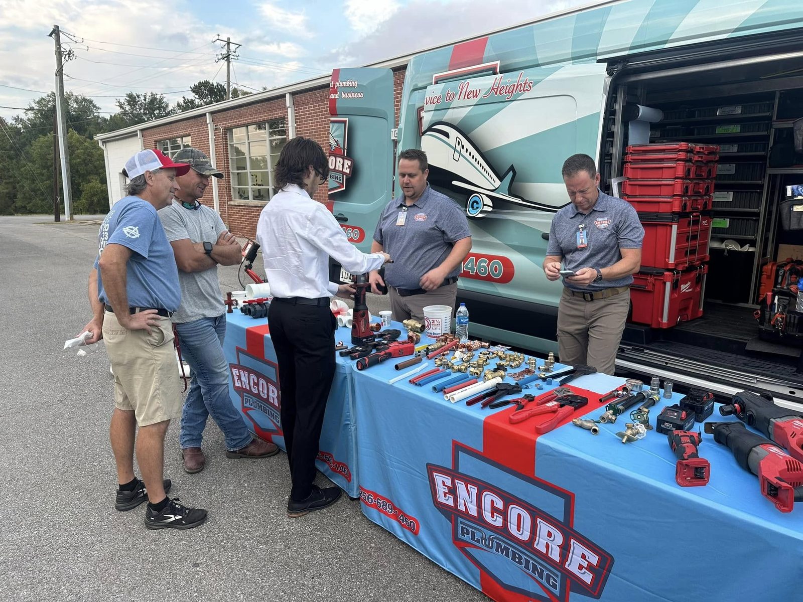 Encore Plumbing team demonstrating tools to visitors at a community event