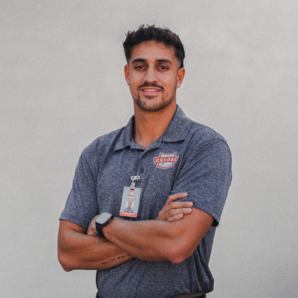 Landon Johnson, Encore Plumbing technician, smiling with arms crossed in a gray Encore polo