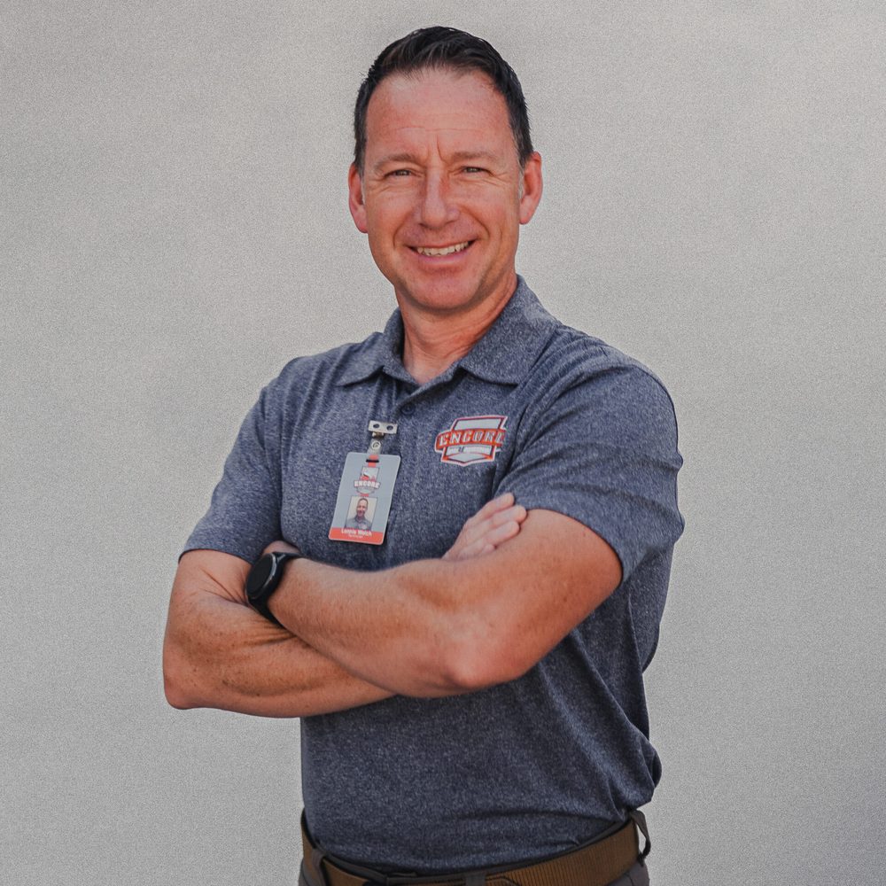 Lonnie Welch, Encore Plumbing technician, smiling with arms crossed in a gray Encore polo