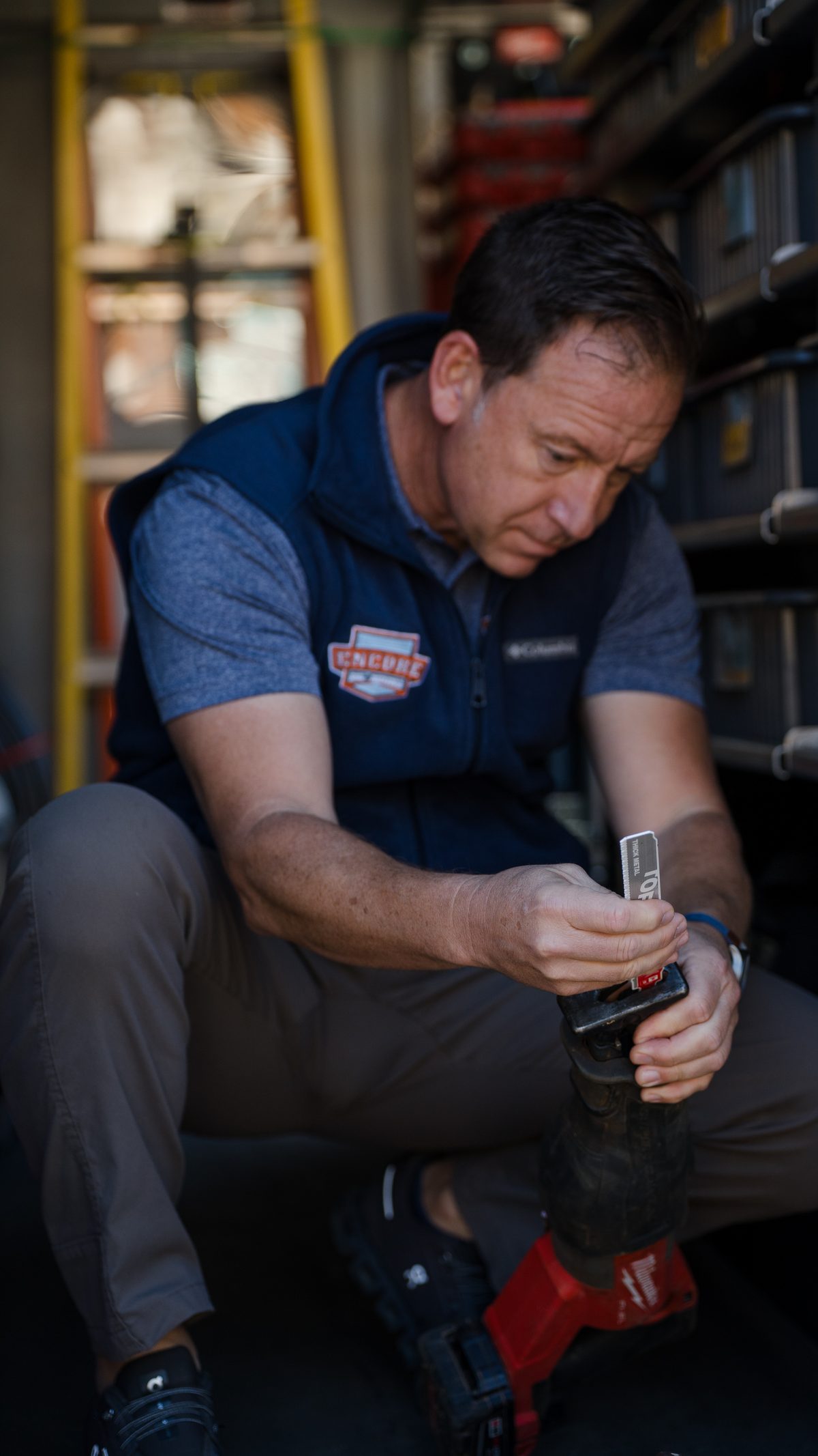 Encore Plumbing technician seated in the van loading a blade into a reciprocating saw