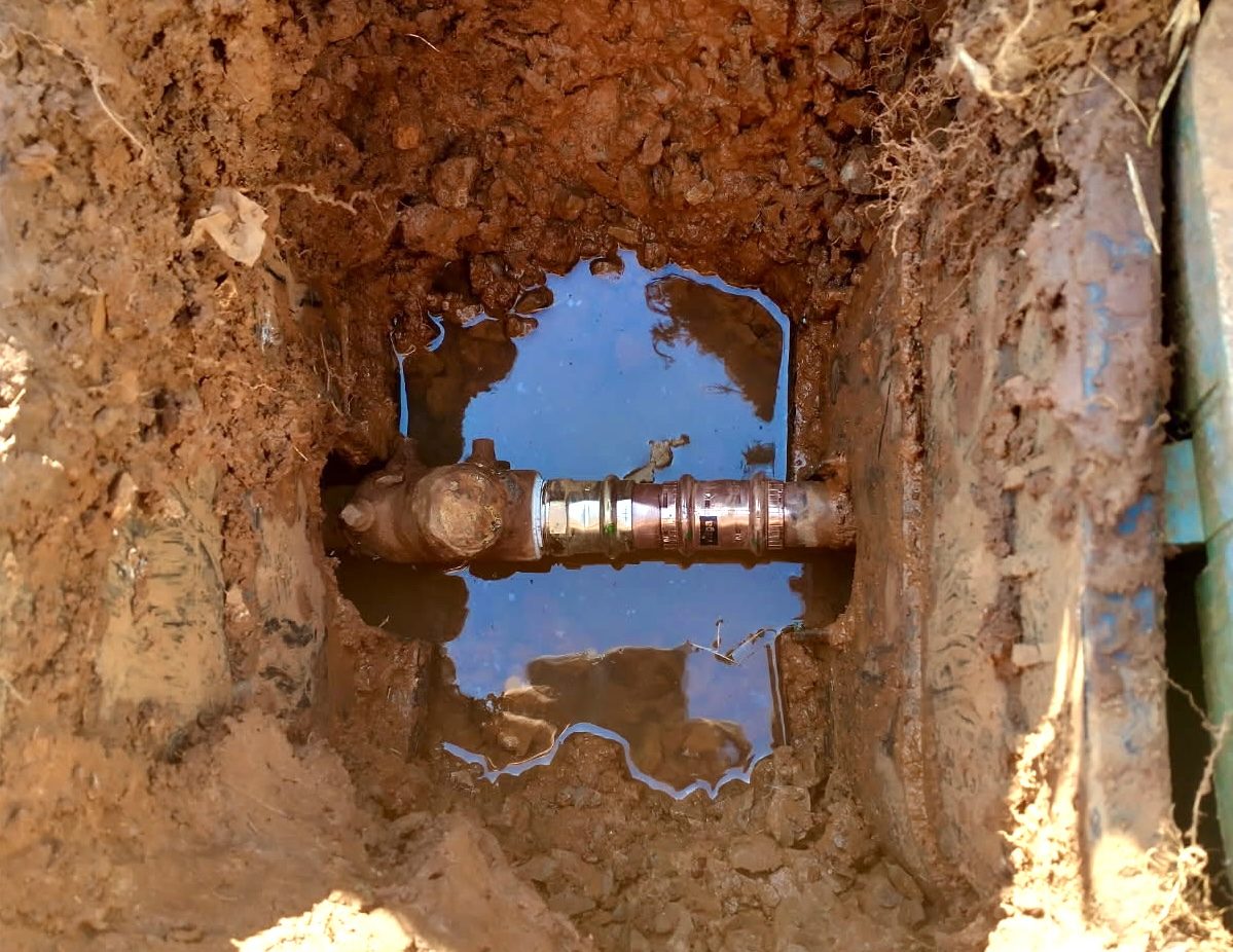 Repaired water line in an excavated hole, a brass valve joined to new pressed copper fittings